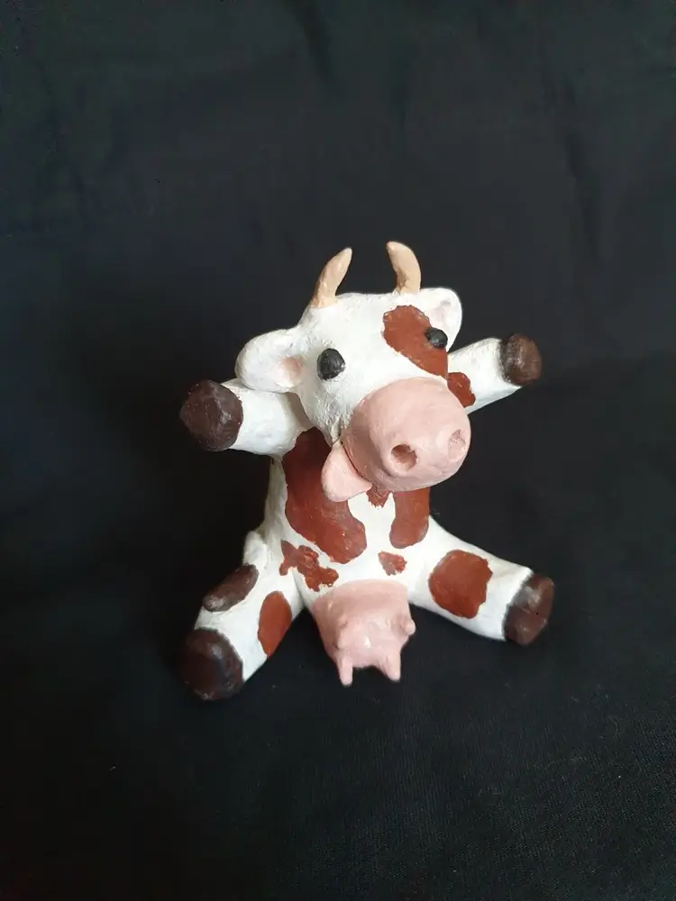 Petite vache assise tendant les pattes