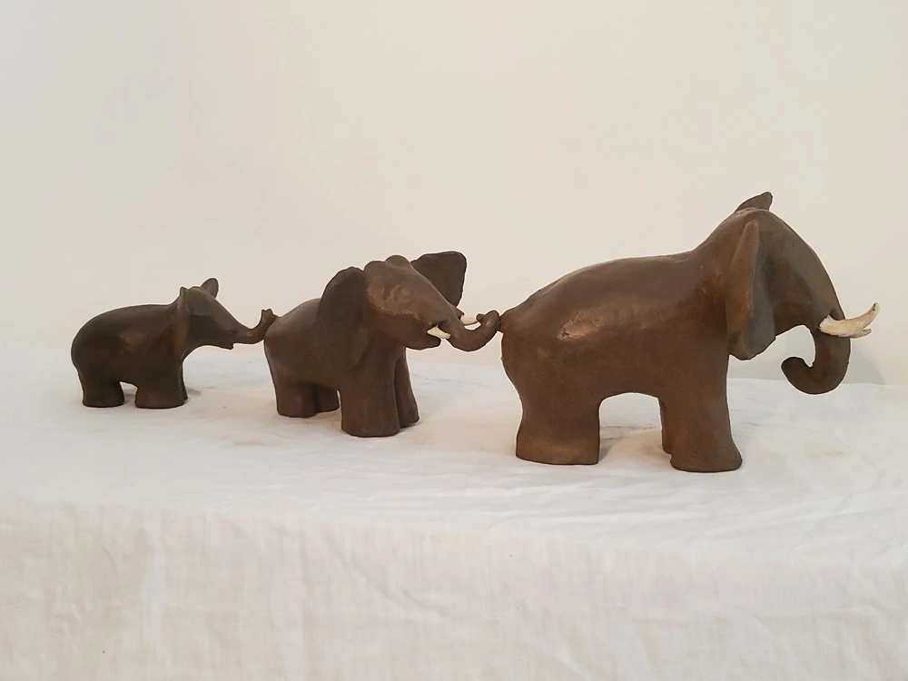 Sculpture trois éléphants à la queue leu leu vers la droite
